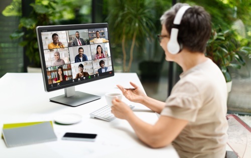 Person on laptop with headphones on and online meeting